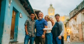Family standing in between two buildings outside in another country.